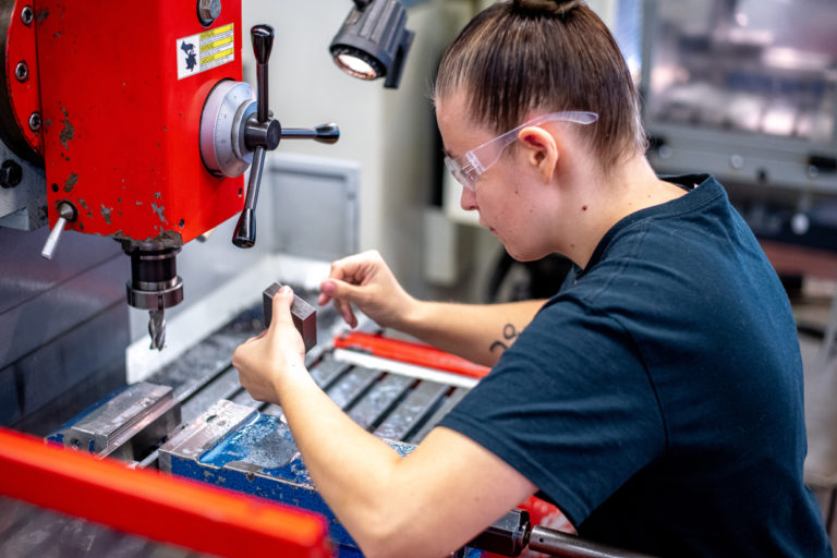 Junge Dame arbeitet an CNC-Maschine